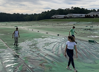 Students walk across a covered waste lagoon